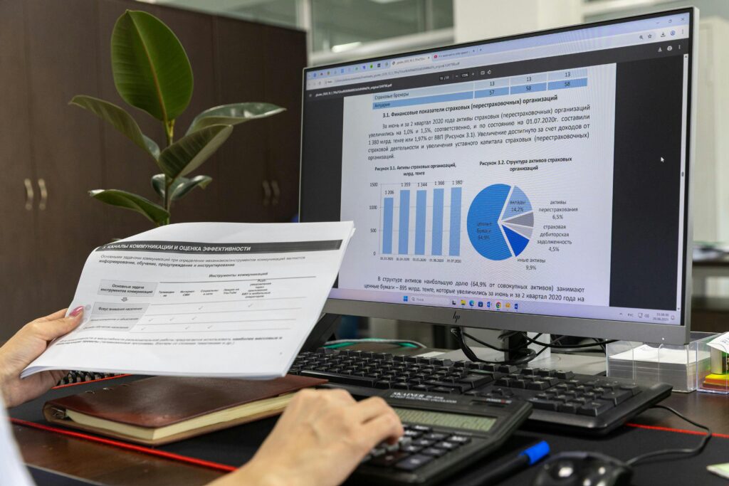 Person analyzing financial data on a computer screen in an office setting.