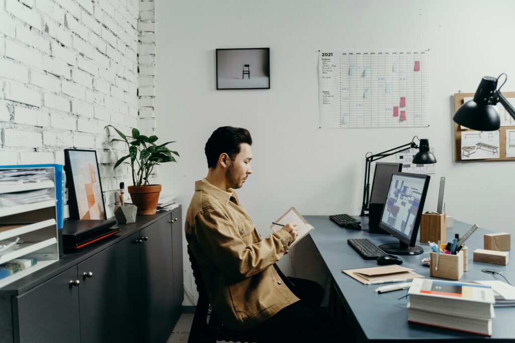Young man in a brown jacket working at a computer in a stylish, modern office.